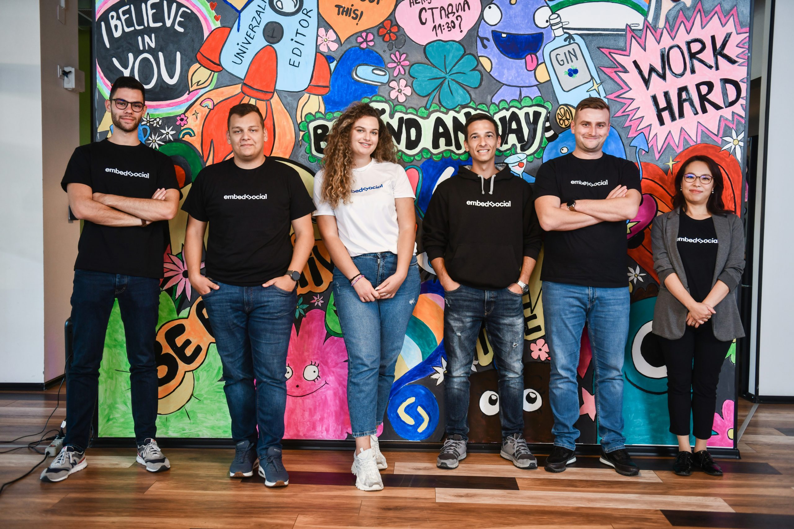 Team standing in front of a colourful mural, representing meaningful appreciation gifts for employees and creative workplace recognition.